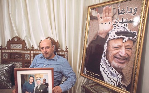 SEORANG lelaki duduk di sisi portret bekas pemimpin Palestin itu di beit Hanina.