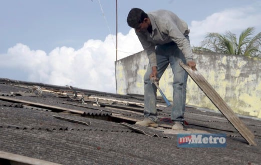 PEKERJA membaiki bumbung rumah yang rosak akibat dipukul angin kencang. FOTO Danial Noordin
