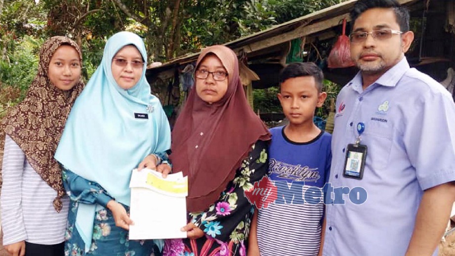 DR Salmee (dua kiri) menyerahkan cek PERKESO kepada Norizah di Kampung Ulu Padang Sanai. FOTO Noorazura Abdul Rahman