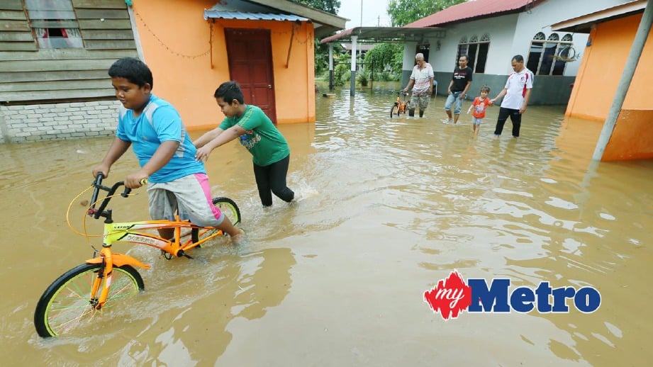 PENDUDUK mengharungi air  banjir kilat di Kampung Gelong Rambai, Mukim Jeram,Tunjang. FOTO Amran Hamid