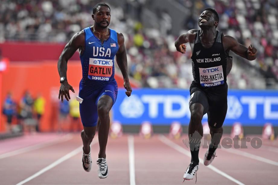 Gatlin (kiri) dan atlet New Zealand, Edward Osei-Nketia bersaing dalam saringan 100m lelaki pada Kejohanan Dunia di Stadium Antarabangsa Khalifa, Doha. FOTO AFP.