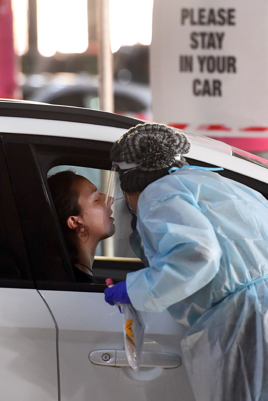 KAKITANGAN perubatan melakukan ujian saringan di parkir sebuah pasar raya di Melbourne pada 23 Jun. FOTO AFP 