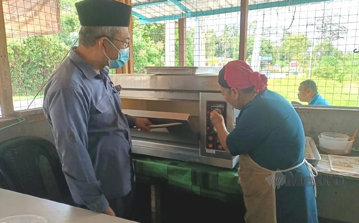 Pengerusi Jawatankuasa Pertanian dan Industri Makanan Negeri Sembilan Datuk Bakri Sawir ketika melihat ketuhar  diterima Rubiah yang mengusahakan kuih bahulu di Kampung Kemin. FOTO ABNOR HAMIZAM ABD MANAP