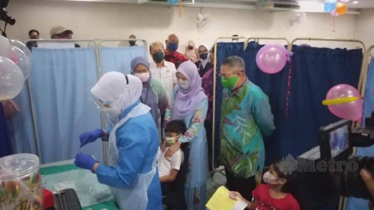 Dr Sirajuddin (berbaju batik warna hijau) sedang meninjau proses pemberian vaksin kepada kanak-kanak. FOTO AIZAT SHARIF