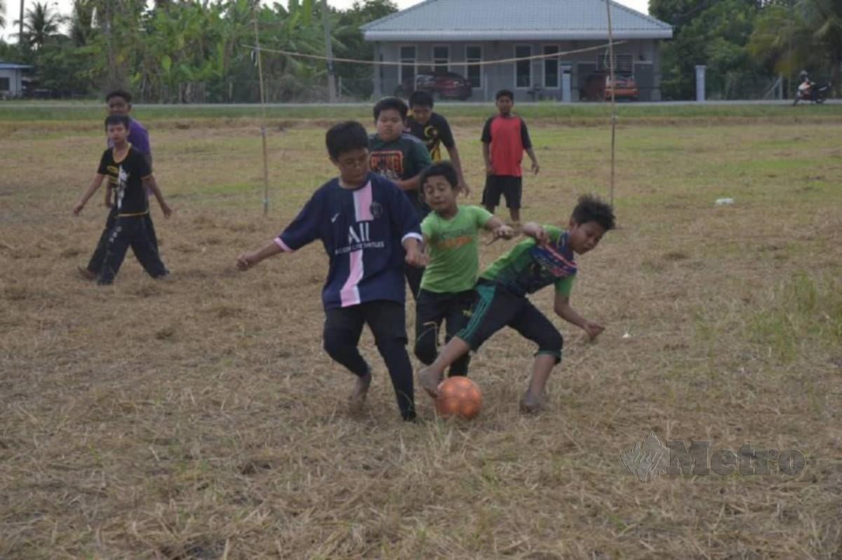 TERTUSUK duri serta permukaan tanah bendang tidak sekata bukanlah penghalang kepada kanak-kanak melepaskan peluang bermain bola bendang. FOTO Aizat Sharif