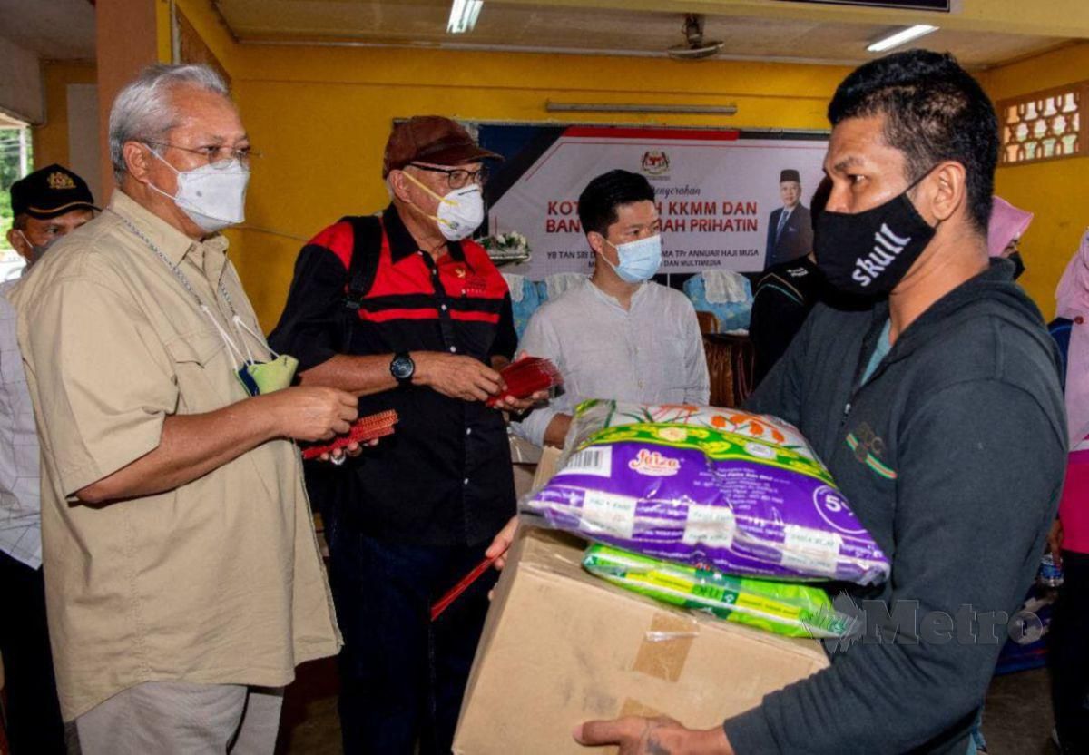 Annuar (kiri) menyerahkan sumbangan kepada salah seorang mangsa banjir ketika Majlis Penyerahan Kotak Kasih KKMM Dan Bantuan Rumah Prihatin di Sekolah Kebangsaan (SK) Kuala Balah. FOTO HAZIRA AHMAD ZAIDI