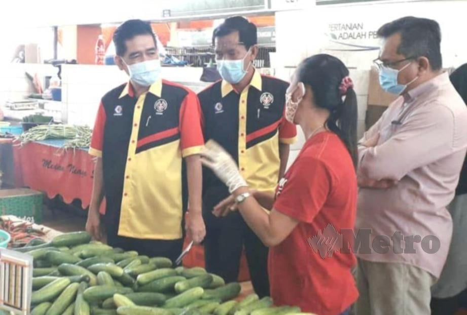 AZMAN (kiri) meninjau harga barang di pusat penjaja Kubah Ria, Kuching. FOTO NORSYAZWANI