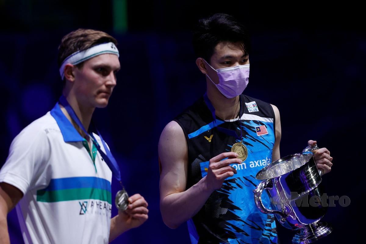 ZII Jia (kanan) bersama trofi kemenangan selepas menewaskan Axelsen (kiri) pada aksi final. FOTO AFP