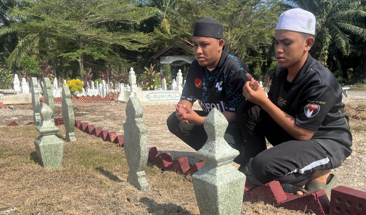ABDUR Rahman (kiri) dan adiknya Abdullah menziarahi pusara ahli keluarga di Tanah Perkuburan Islam Masjid Ubuddiah, Parit Limbong, Parit Jawa. FOTO BERNAMA
