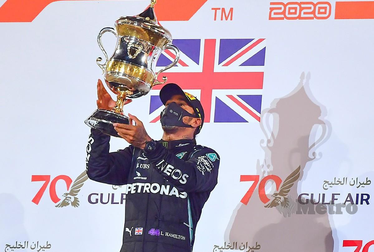 HAMILTON menjulang trofi kemenangan selepas mengungguli GP Bahrain. FOTO AFP
