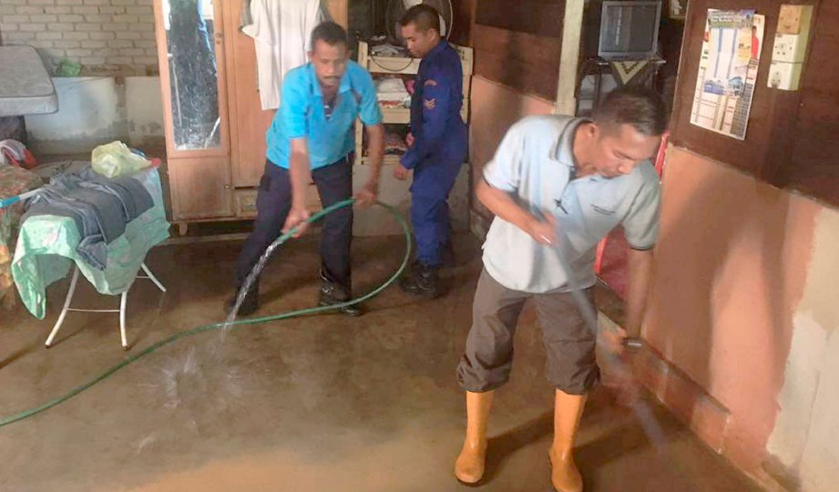 ANGGOTA sukarelawan membantu membersihkan rumah mangsa banjir. 