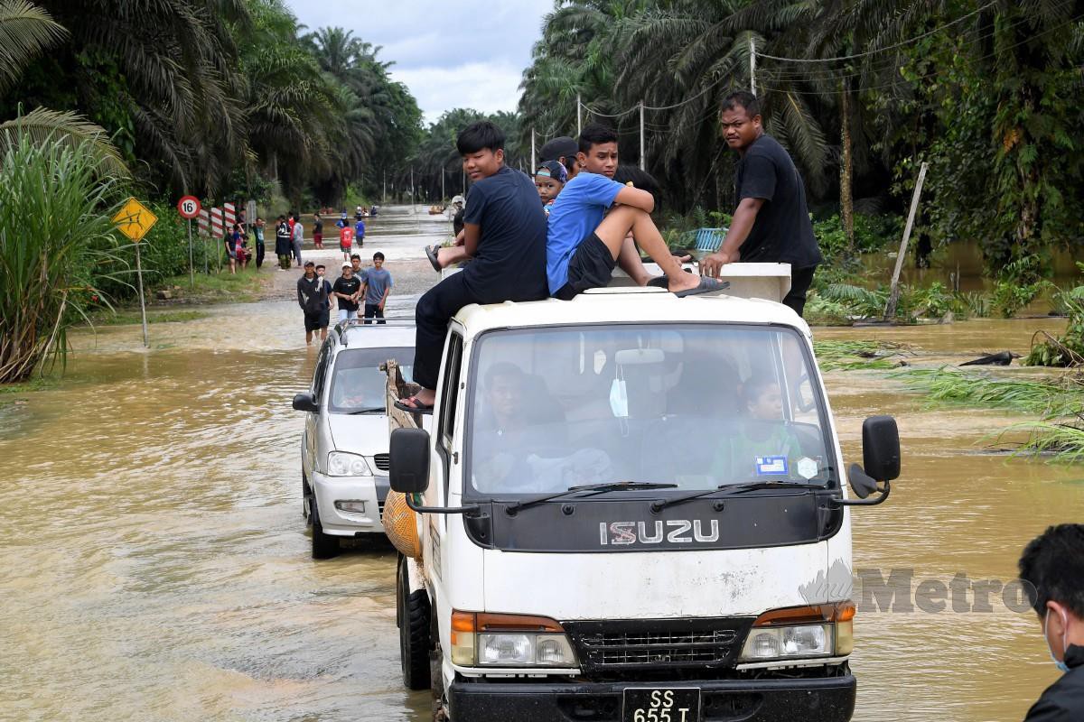 ORANG ramai menaiki lori untuk keluar selepas banjir melanda Kampung Sungai Manjang di Sandakan. FOTO Bernama