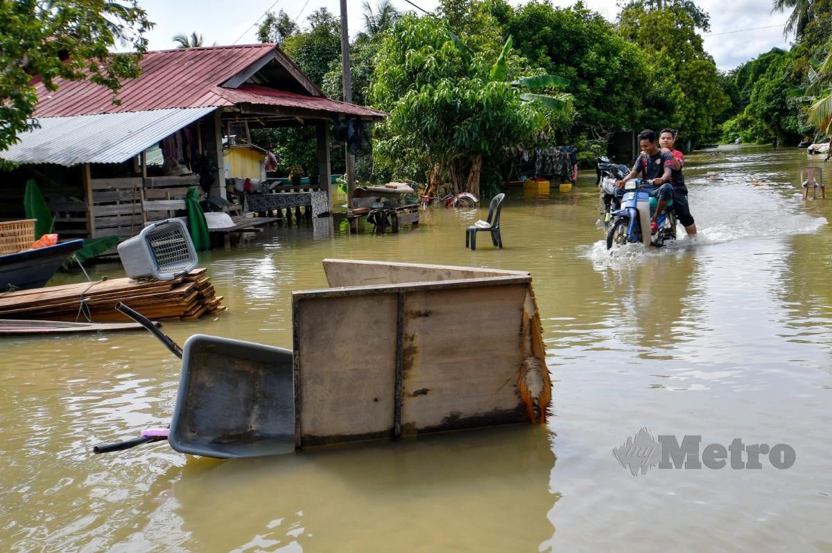 PENDUDUK meredah banjir menggunakan motosikal di Kampung Tersang, Rantau Panjang. FOTO Bernama 