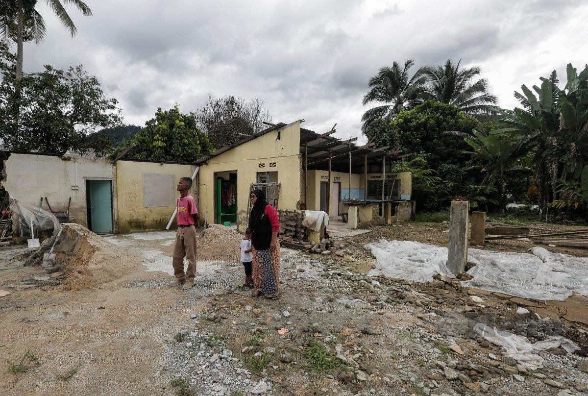 MD Nor  dan Siti Sufiah di hadapan rumah mereka yang musnah akibat banjir pada 2021.