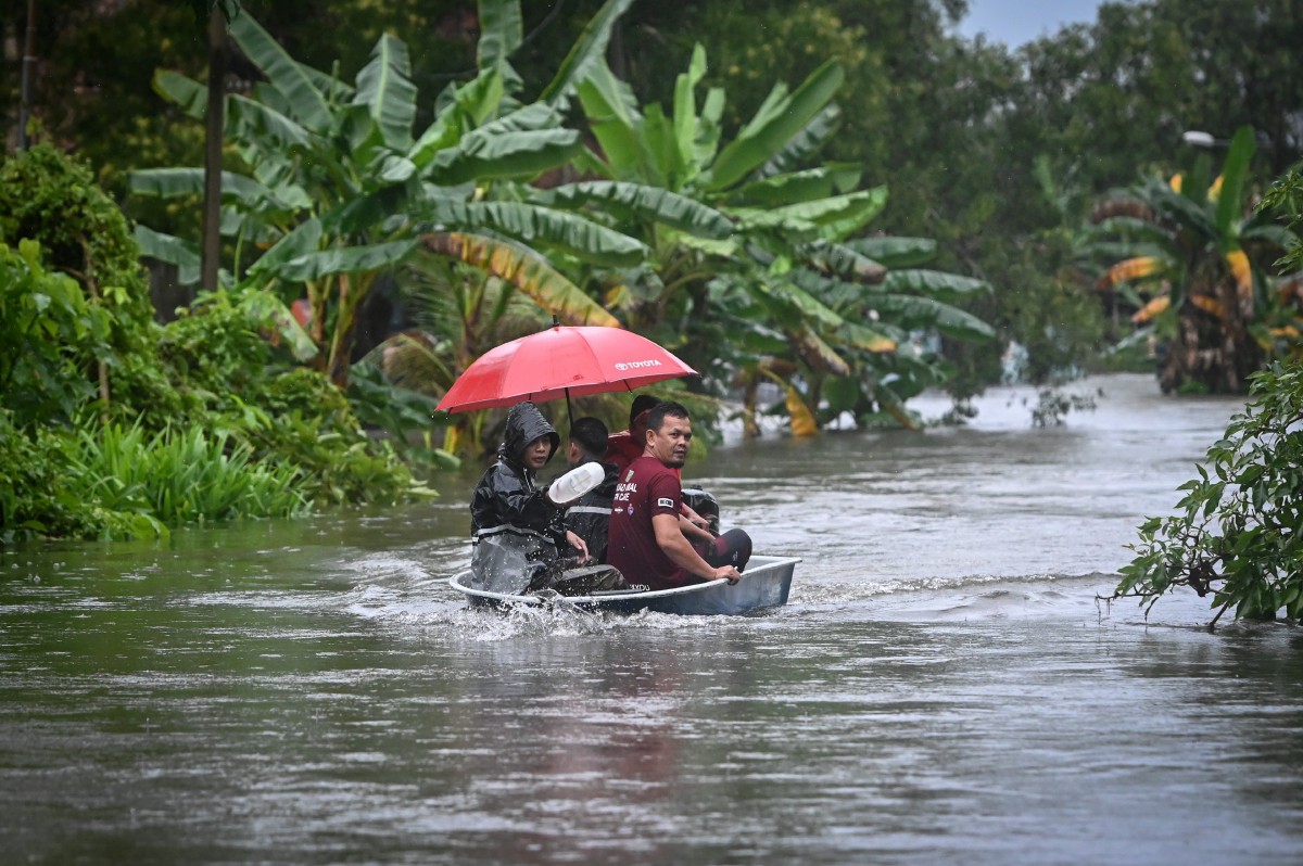SEBAHAGIAN penduduk meredah banjir dengan menaiki bot untuk ke tempat yang lebih selamat di Kampung Gong Baru hari ini.  FOTO Bernama 