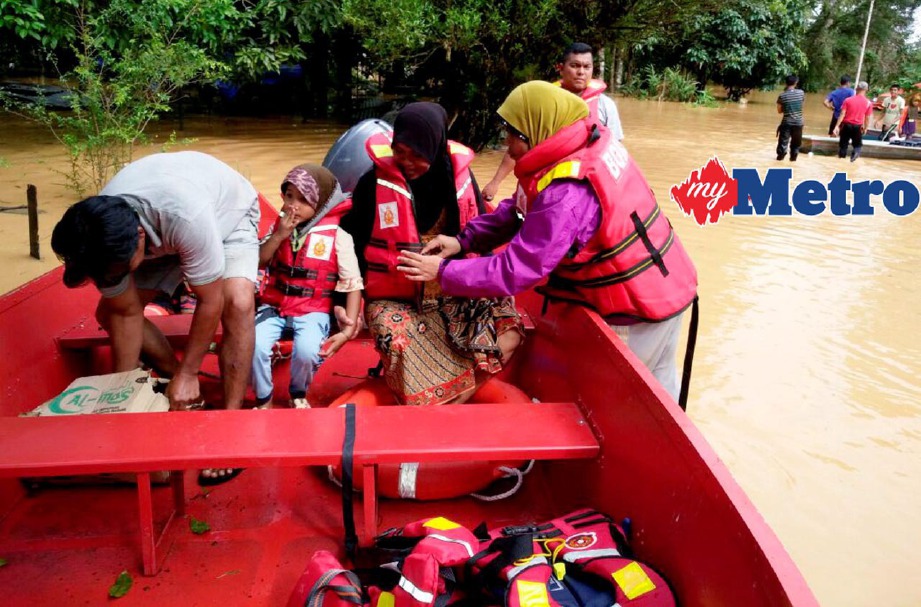 Anggota Bomba dan Penyelamat memindahkan mangsa banjir di Kampung Limau Kasturi apabila air sungai mulai naik mendadak sejak awal pagi. FOTO Ramli Ibrahim 