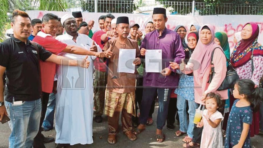 PENDUDUK Kampung Tanjung Langsat menunjukkan surat bantahan pelantikan ketua kampung baharu yang bukan anak jati atau penduduk asal kampung berkenaan, hari ini. FOTO Izlaily Nurul Ain Hussein.