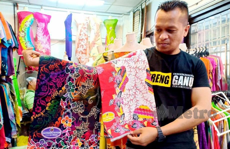 SAIFUL Bahrin menunjukkan dua batik sarung kilang dijualnya dengan corak batik moden kontemporari yang lebih murah dan mendapat sambutan pelanggan di Kuala Terengganu. FOTO Ahmad Rabiul Zulkifli.