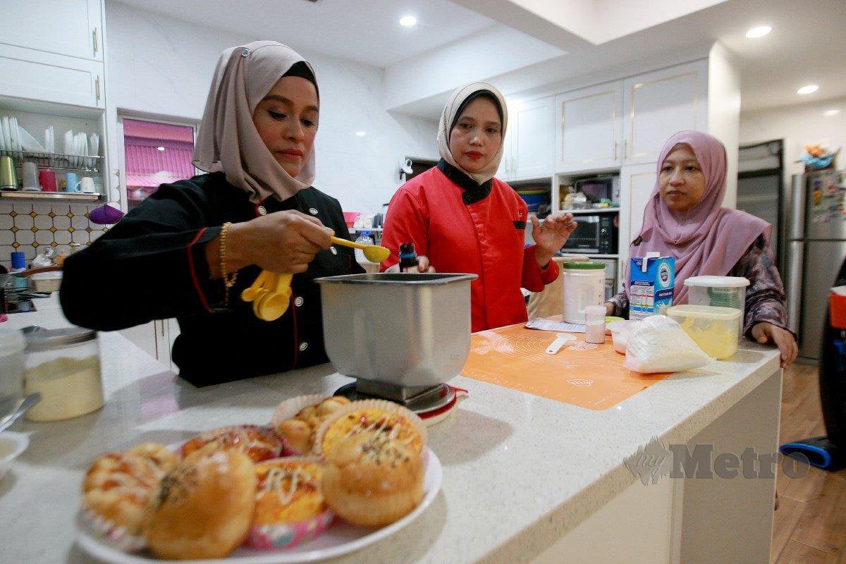 SAITINA bersama anak didiknya, Julia menunjukkan hasil roti yang dipelajari ketika menyertai bengkel pembuatan kek dan bakeri di Bandar Puteri, Klang.