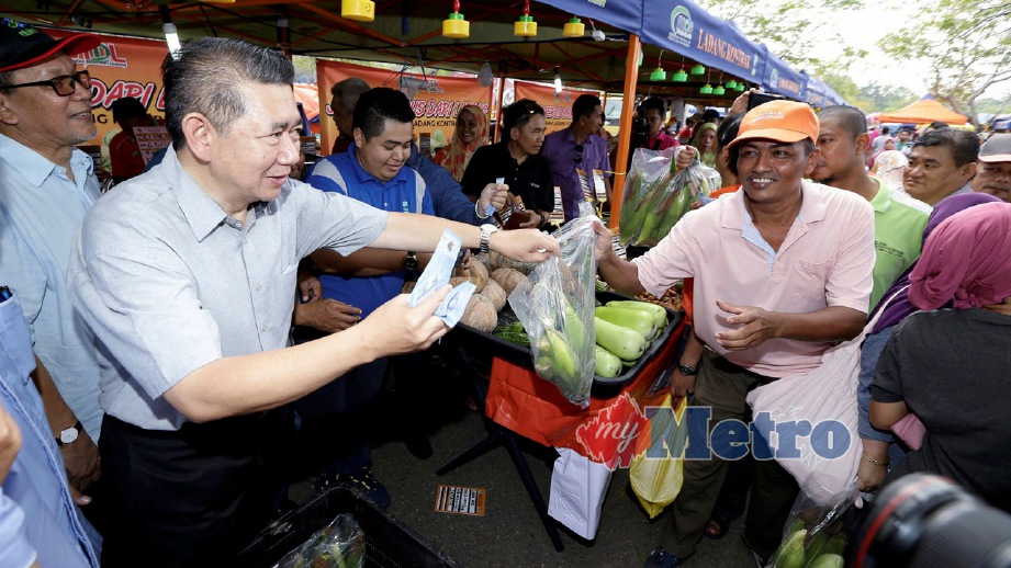 SALAHUDDIN (dua kiri) melakukan jualan jagung kepada pembeli selepas Majlis Pelancaran Jimat Belanja Aidlfitri 2018. FOTO Roslin Mat Tahir