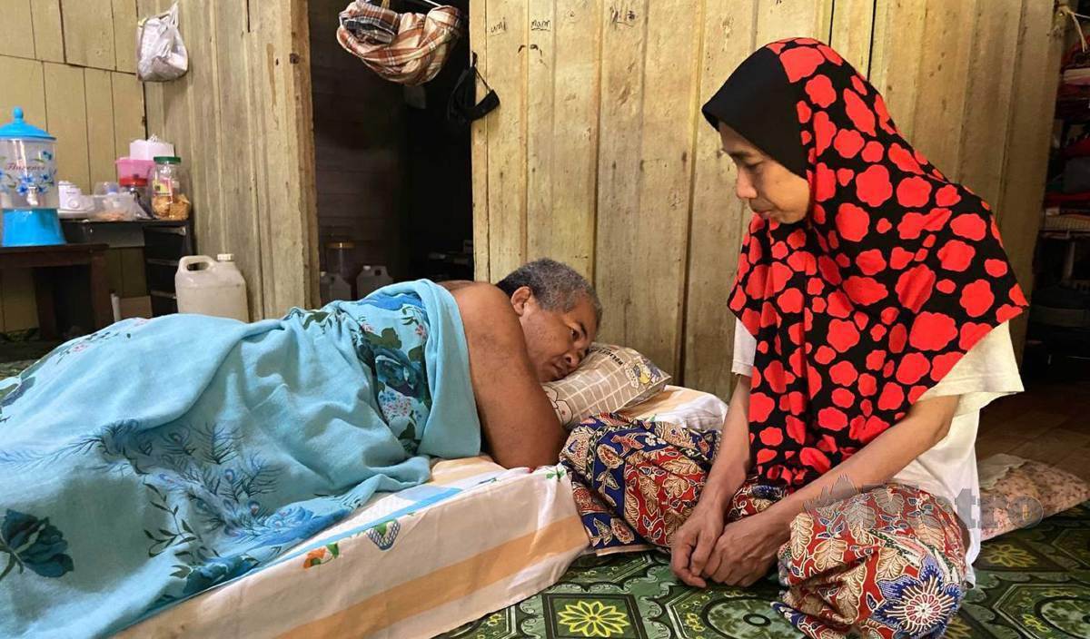 ROSNI setia di sisi suaminya, Md Burhan yang menghidap penyakit kencing manis saraf dan buah pinggang tahap empat ketika ditemui di rumah mereka di Kampung Guchil. FOTO Hazira Ahmad Zaidi