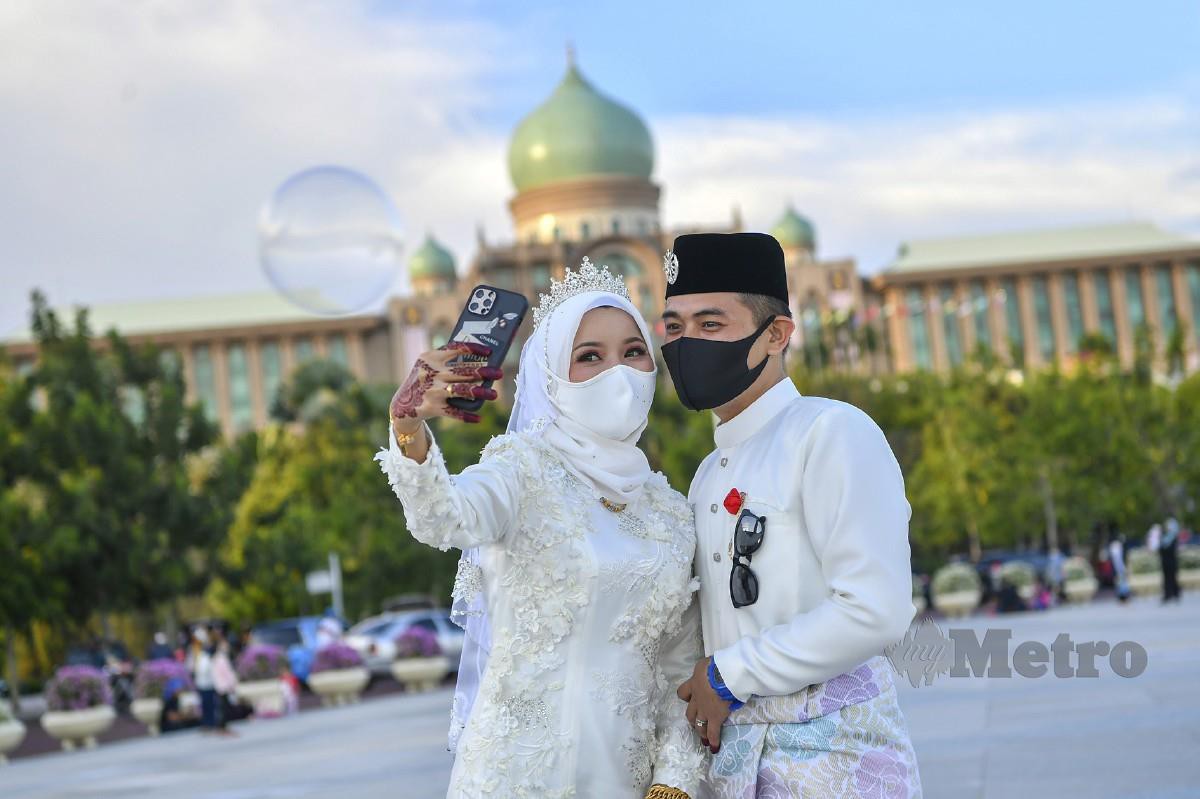 JUNE Asmerahawa dengan pasangannya Mohd Fauzi berswafoto berlatar belakangkan Bangunan Perdana Putra di Dataran Putra Putrajaya. FOTO Bernama 
