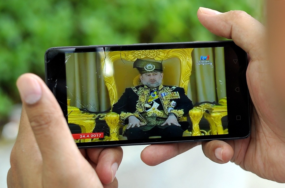 SEORANG pengunjung tidak melepaskan peluang untuk mengikuti secara langsung Istiadat Pertabalan Yang di-Pertuan Agong Ke-XV Sultan Muhammad V menerusi telefon bimbit di KLCC. FOTO Bernama