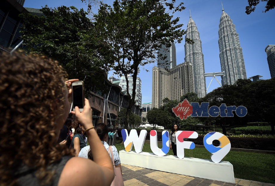 PESERTA bergambar kenangan berlatar belakang Menara Berkembar Petronas sempena Forum Bandar Sedunia Kesembilan (WUF9). FOTO Bernama