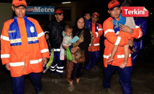 ANGGOTA Jabatan Pertahanan Awam (JPAM) memindahkan penduduk Kampung Mulong, Kota Bharu, selepas kawasan itu dilanda banjir. FOTO Bernama