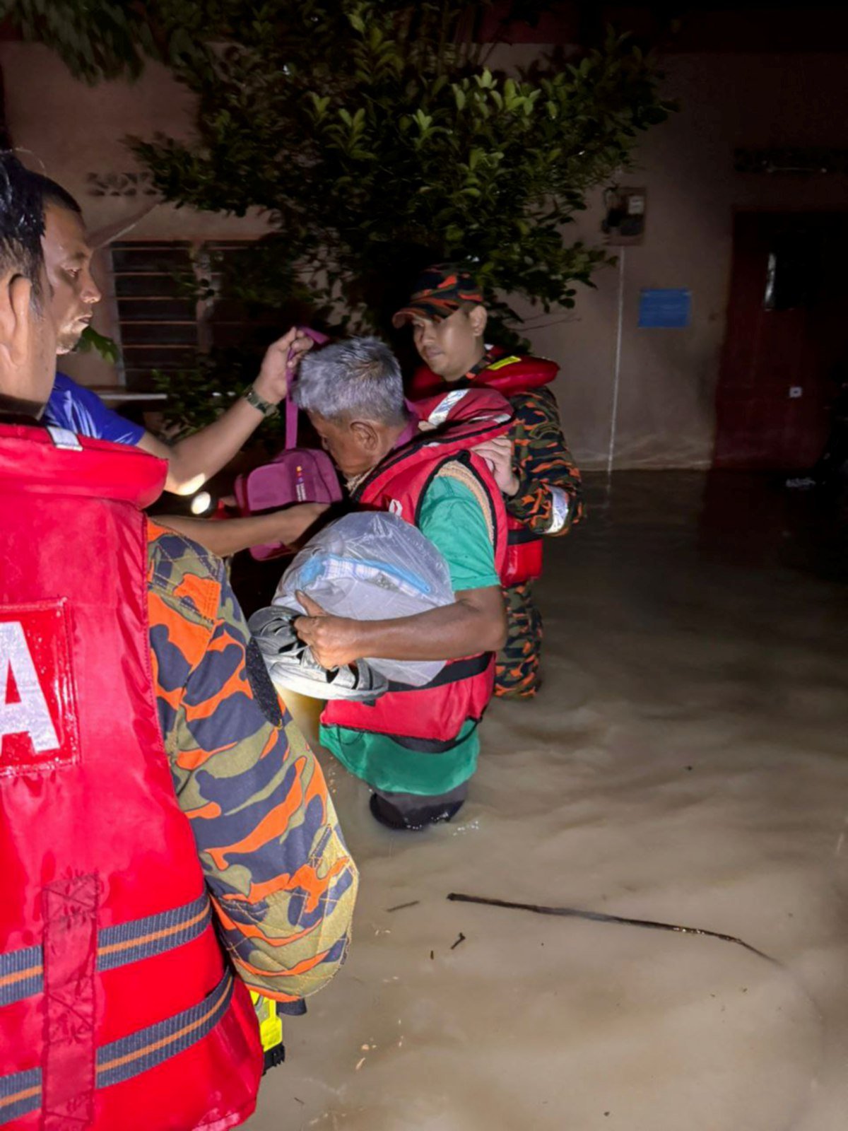 ANGGOTA bomba membantu memindahkan mangsa banjir di Parit ke PPS SK Simpang 3, malam tadi. FOTO Ihsan JBPM