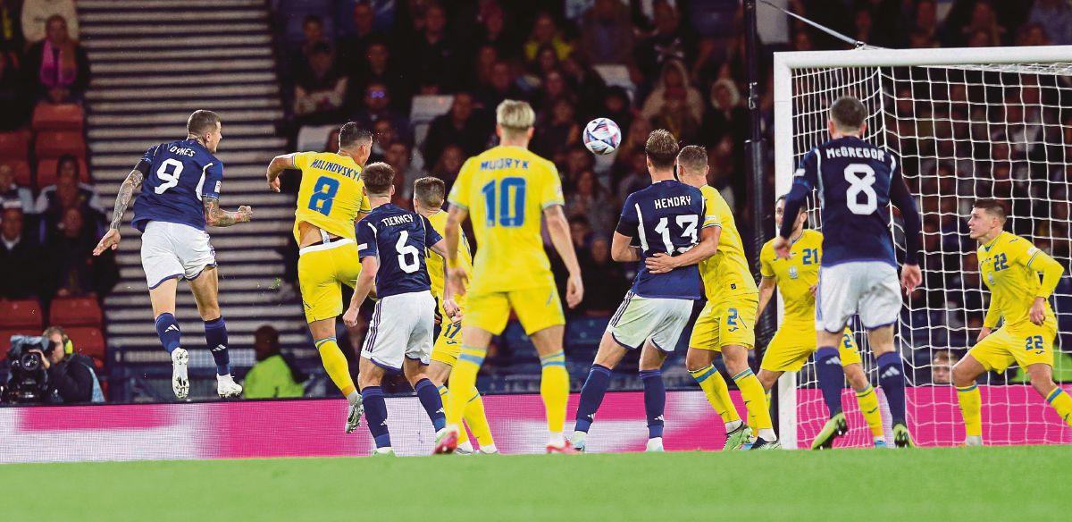 AKSI  Dykes (kiri) menanduk masuk gol kedua Scotland. FOTO AFP
