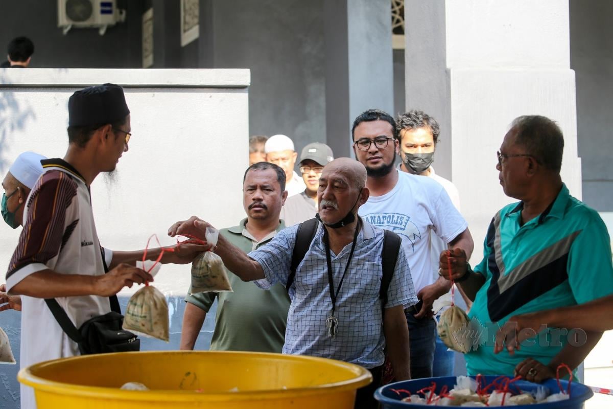 Orang ramai beratur mengambil bubur lambuk pada tinjauan bubur lambuk Masjid Kampung Baru. FOTO ASWADI ALIAS.