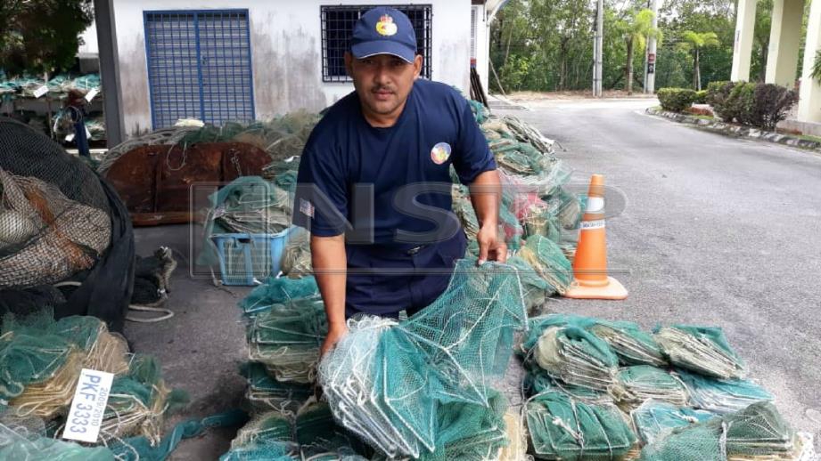 MANSOR menunjukkan bubu naga yang dirampas sepanjang empat hari operasi sekitar perairan Segari, Manjung. FOTO Ihsan Jabatan Perikanan Perak.