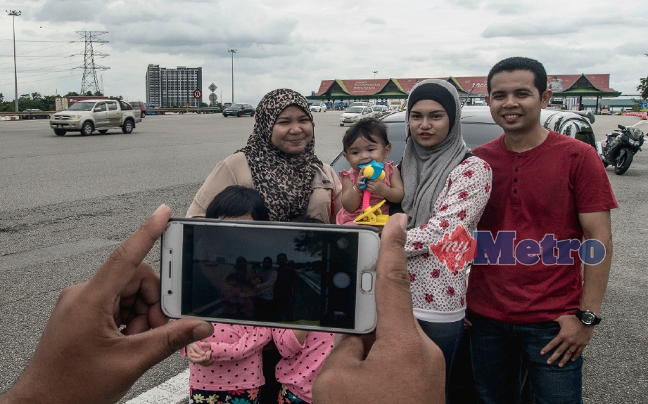 (Gambar fail) Siti Zulaiha Norizam (dua kanan) dan Mohamad  Saiful Rosuri (kanan) bergambar berlatarbelakangkan Plaza Tol Batu 3, Shah Alam yang akan mula dirobohkan. FOTO Muhammad Sulaiman 