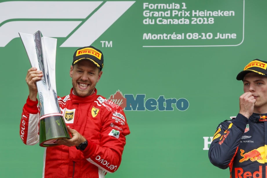 PEMANDU Ferrari, Sebastian Vettel (kiri) menjulang trofi kekemenangan di GP Canada. FOTO EPA-EFE