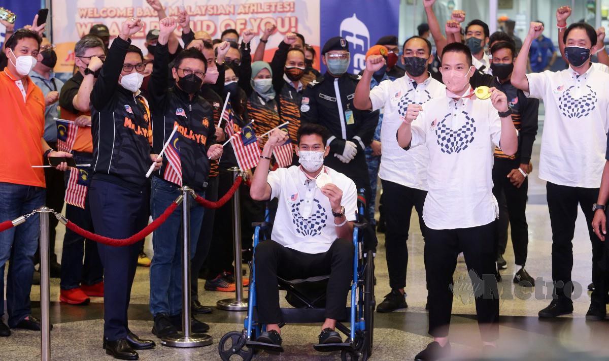 Atlet paralimpik Abdul Latif (bekerusi roda) dan Liek Hou (3, kanan) ketika diraikan kepulangan kontinjen Malaysia di KLIA. FOTO Mohd Fadli Hamzah