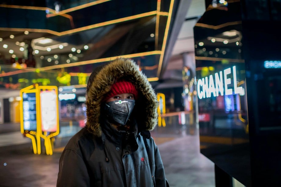 WANITA memakai penutup hidung dan mulut berjalan di dalam pusat beli-belah di Beijing. FOTO AFP 