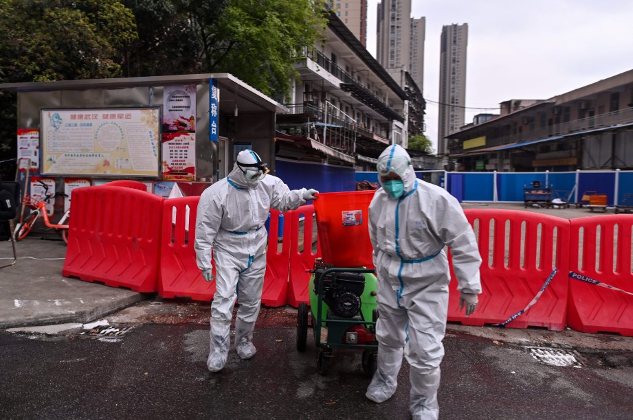 PEKERJA memakai sut perlindungan berhampiran Pasar Hunan, Wuhan yang dipercayai punca wabak Covid-19. Pasar itu masih ditutup. FOTO AFP 
