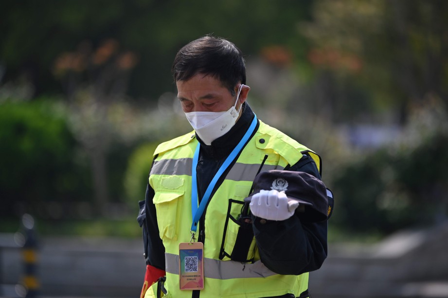 PEGAWAI polis di China menundukkan kepada dan berdiam diri selama tiga minit bagi memperingati mangsa Covid-19 di negara itu. FOTO AFP 