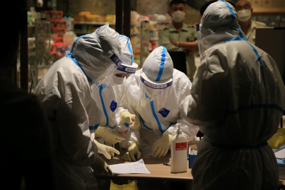 FOTO pada 25 Julai menunjukkan petugas kesihatan menjalankan ujian saringan Covid-19 kepada pengunjung sebuah pusat beli-belah di Dalian. FOTO AFP) / China OUT