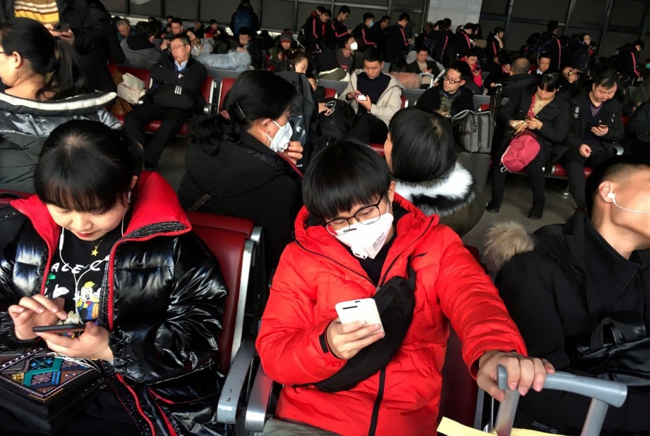 PENUMPANG memakai penutup hidung dan mulut di ruang menunggu stesen kereta api di Wuhan. FOTO Reuters