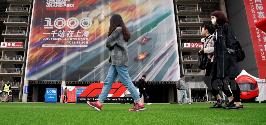 ORANG ramai berjalan melewati poster Grand Prix China di Shanghai. FOTO Reuters 