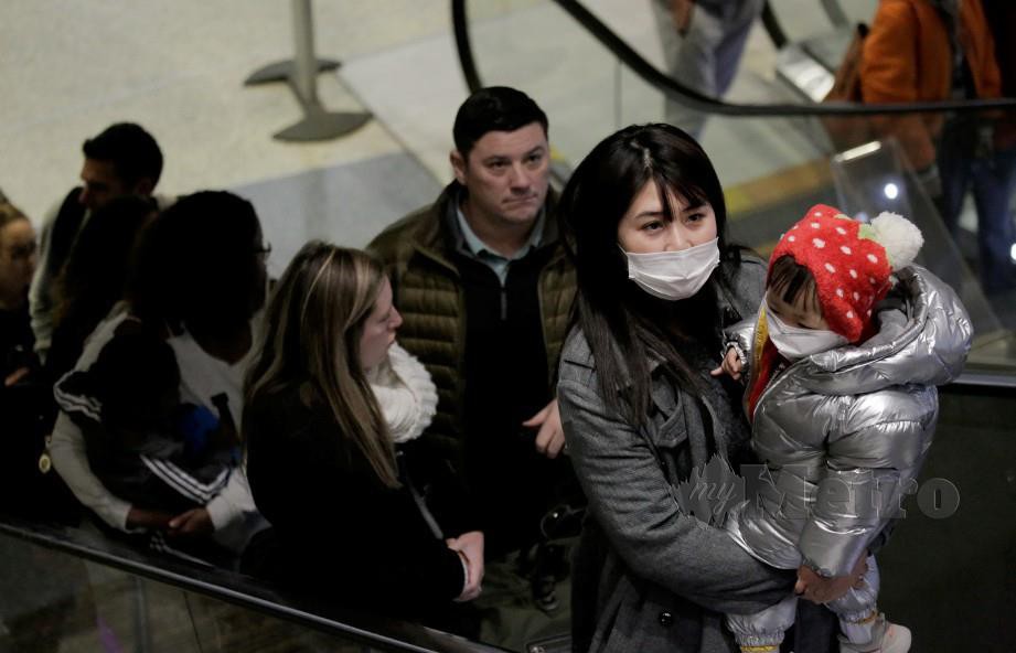 PELANCONG China memakai topeng muka dan alkan diperiksa sebaik tiba di lapangan terbang di Amerika Syarikat. FOTO REUTERS.
