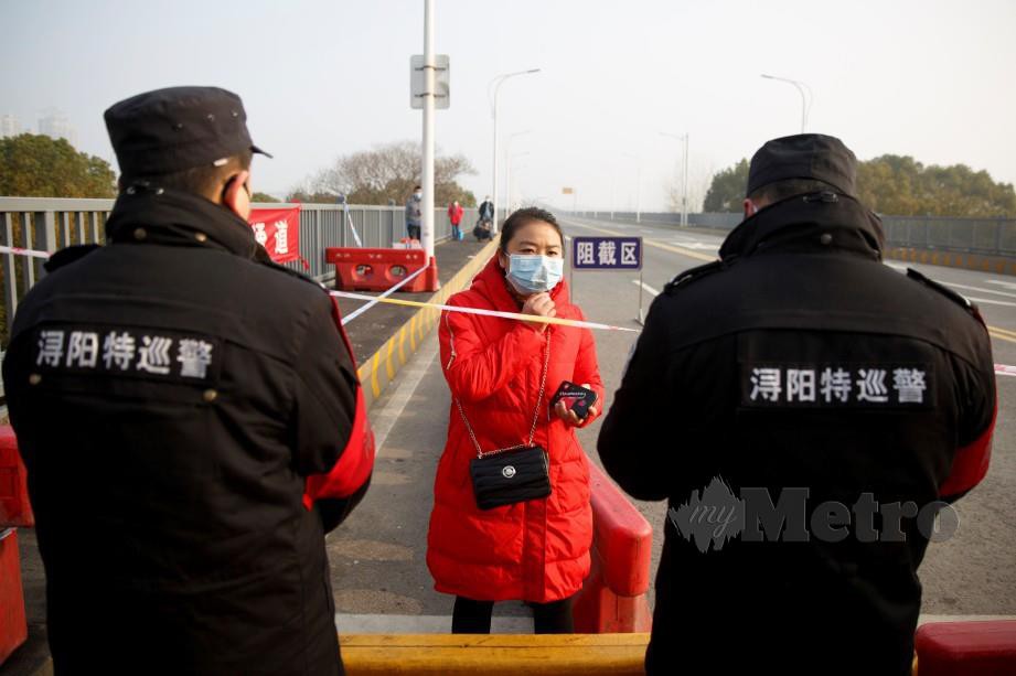 SEORANG wanita yang baru tiba di Hubei, bercakap dengan pegawai keselamatan sebelum dibenarkan memasuki kawasan Jiangxi. FOTO Reuters