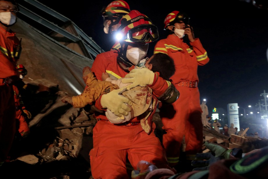SEORANG mangsa kanak-kanak diselamatkan dari runtuhan hotel berkenaan. China Daily/ Reuters 