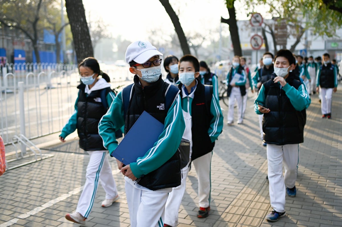 SEKUMPULAN pelajar yang memakai pelitup muka berjalan di Beijing. FOTO AFP 