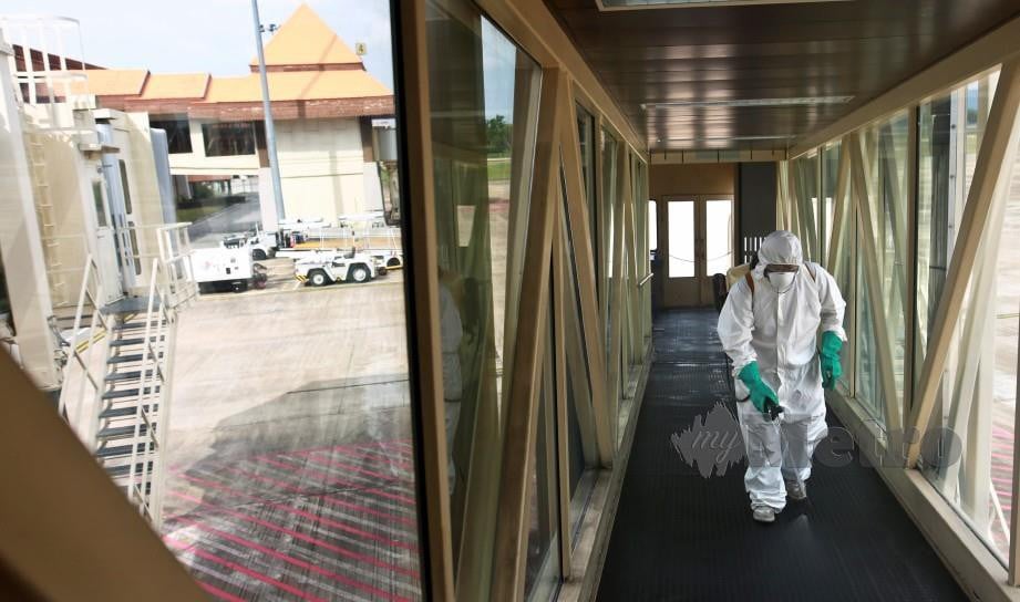 ANGGOTA JBPM Terengganu bersama Jabatan Kesihatan dan Persekitaran MBKT melakukan proses disinfeksi di Lapangan Terbang Sultan Mahmud.  FOTO Ghazali Kori