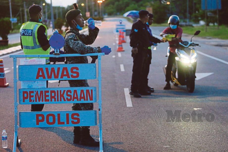 ANGGOTA polis bersama tentera berbuka puasa sambil menyampaikan juadah kepada penunggang motosikal semasa bertugas di sekatan jalan raya di Kampung Rhu Renggeh, Marang. FOTO Ghazali Kori