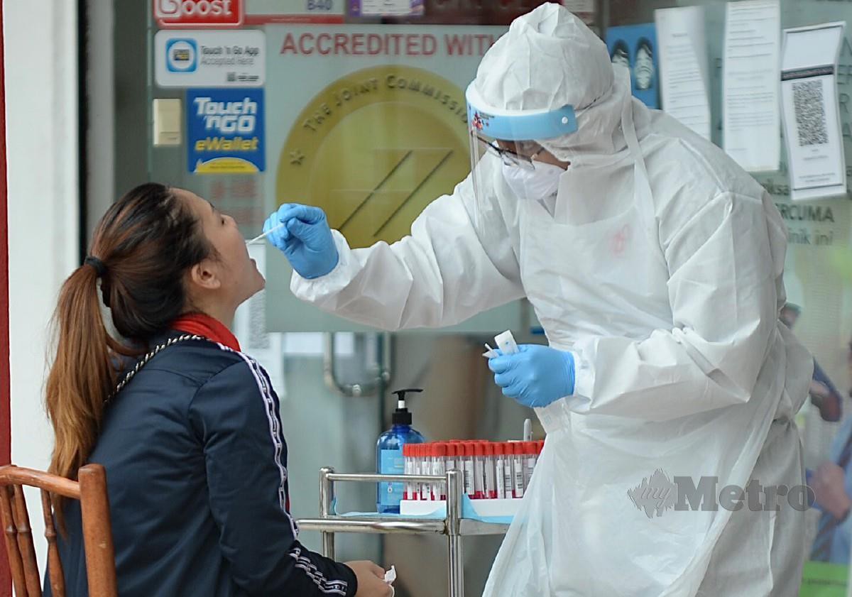SEORANG wanita melakukan ujian saringan Covid-19 di sebuah pusat kesihatan swasta. FOTO Khairul Azhar Ahmad.