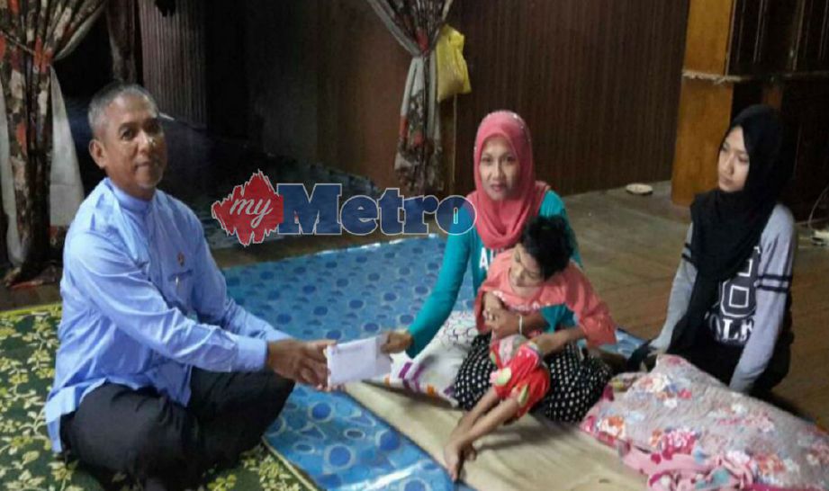 Dr Nik Mohd Azlan (kiri) menyampaikan sumbangan kepada Salihah di Kampung Kubang Keranji, Kota Bharu, hari ini. FOTO Nik Abdullah Nik Omar